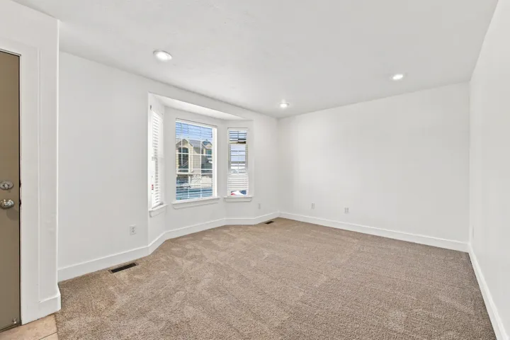 Bay window with white blinds, recessed lighting, and neutral carpet flooring