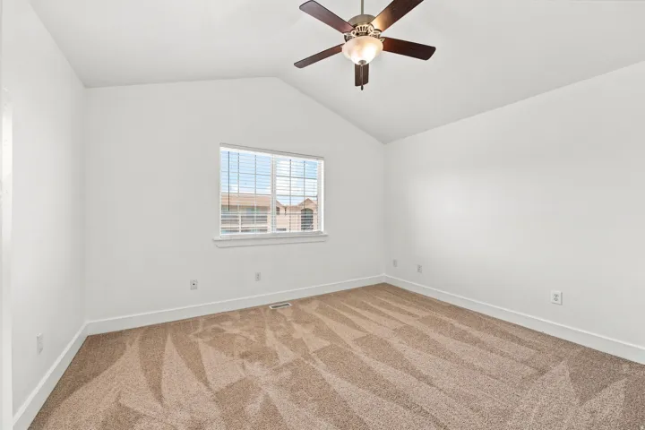 Vaulted ceiling with a ceiling fan, neutral carpet flooring, white walls, and a window with blinds