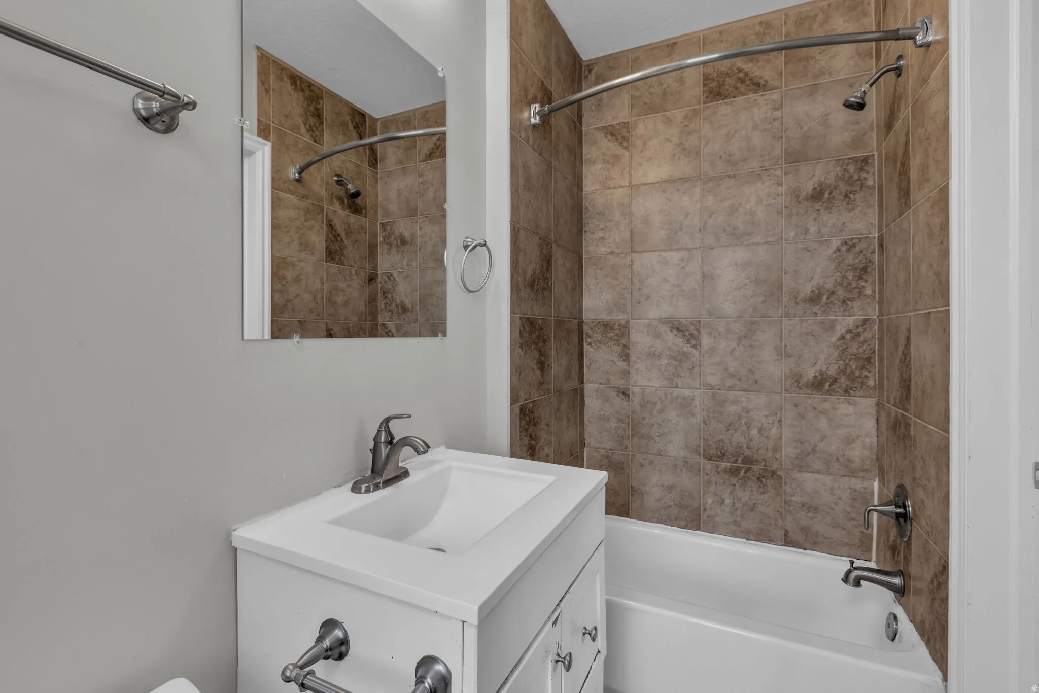 White vanity with an integrated sink, brushed nickel faucet, and a wall-mounted mirror