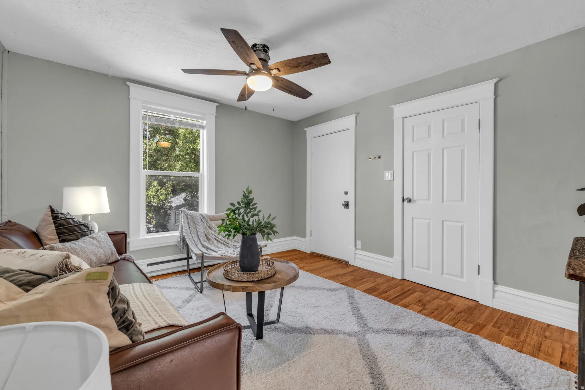 Wood-finish flooring, ceiling fan with light, white trim and baseboards, single window, and panel doors