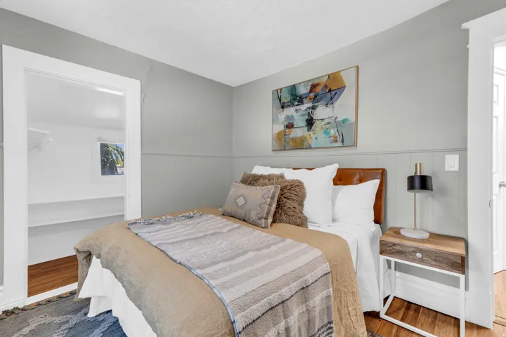 Paneling accent wall, hardwood-style flooring, white trim, recessed closet, built-in shelving