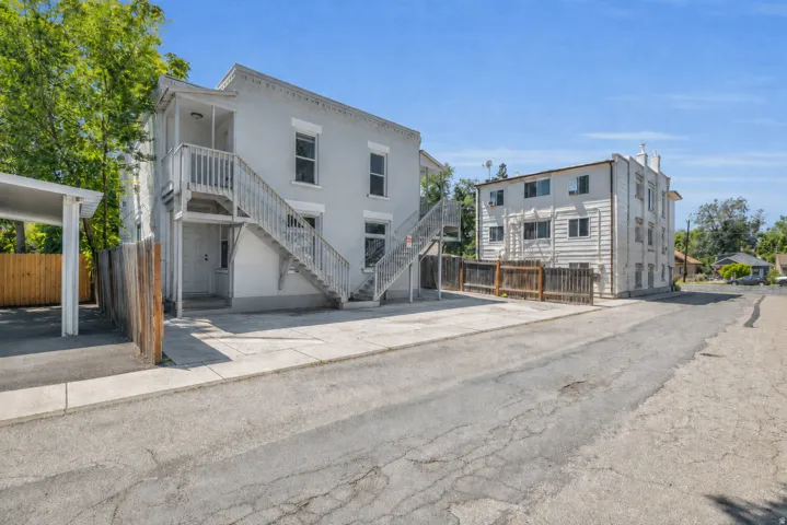 Multi-unit property featuring exterior stairwells, a covered parking structure, and a wood fence