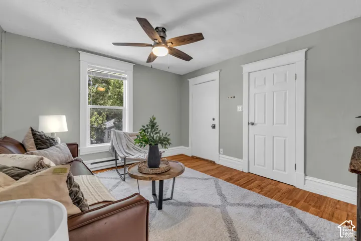 Wood-finish flooring, ceiling fan with light, white trim and baseboards, single window, and panel doors