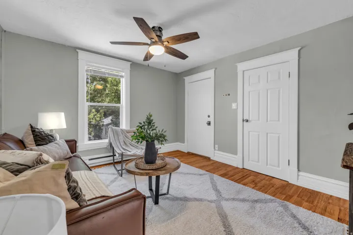 Wood-finish flooring, ceiling fan with light, white trim and baseboards, single window, and panel doors
