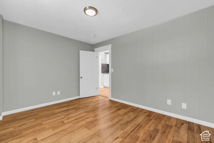 Wood-finish flooring, white trim, recessed ceiling light, paneled wall accent, and a white interior door