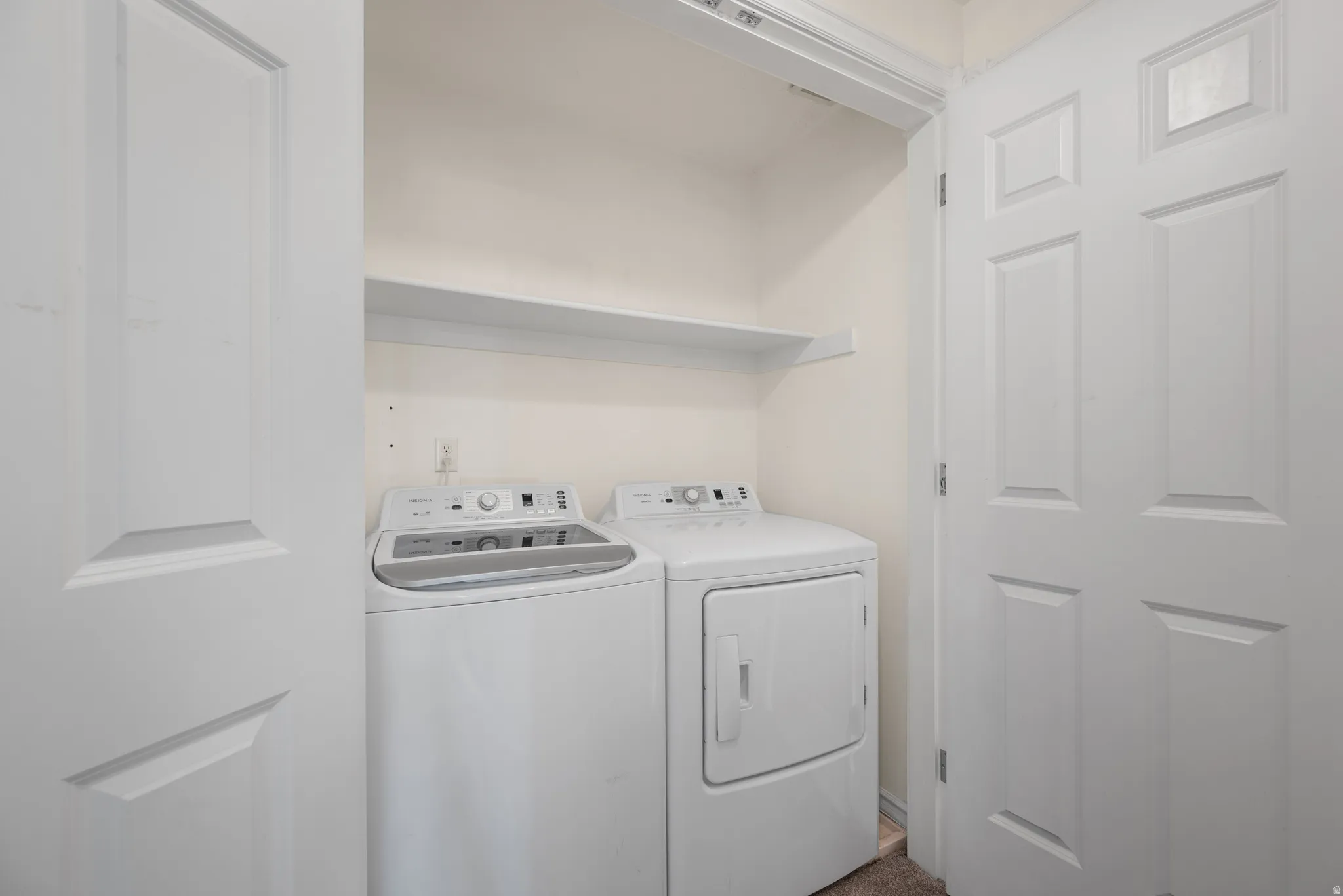 Dedicated laundry area with white appliances and built-in shelving