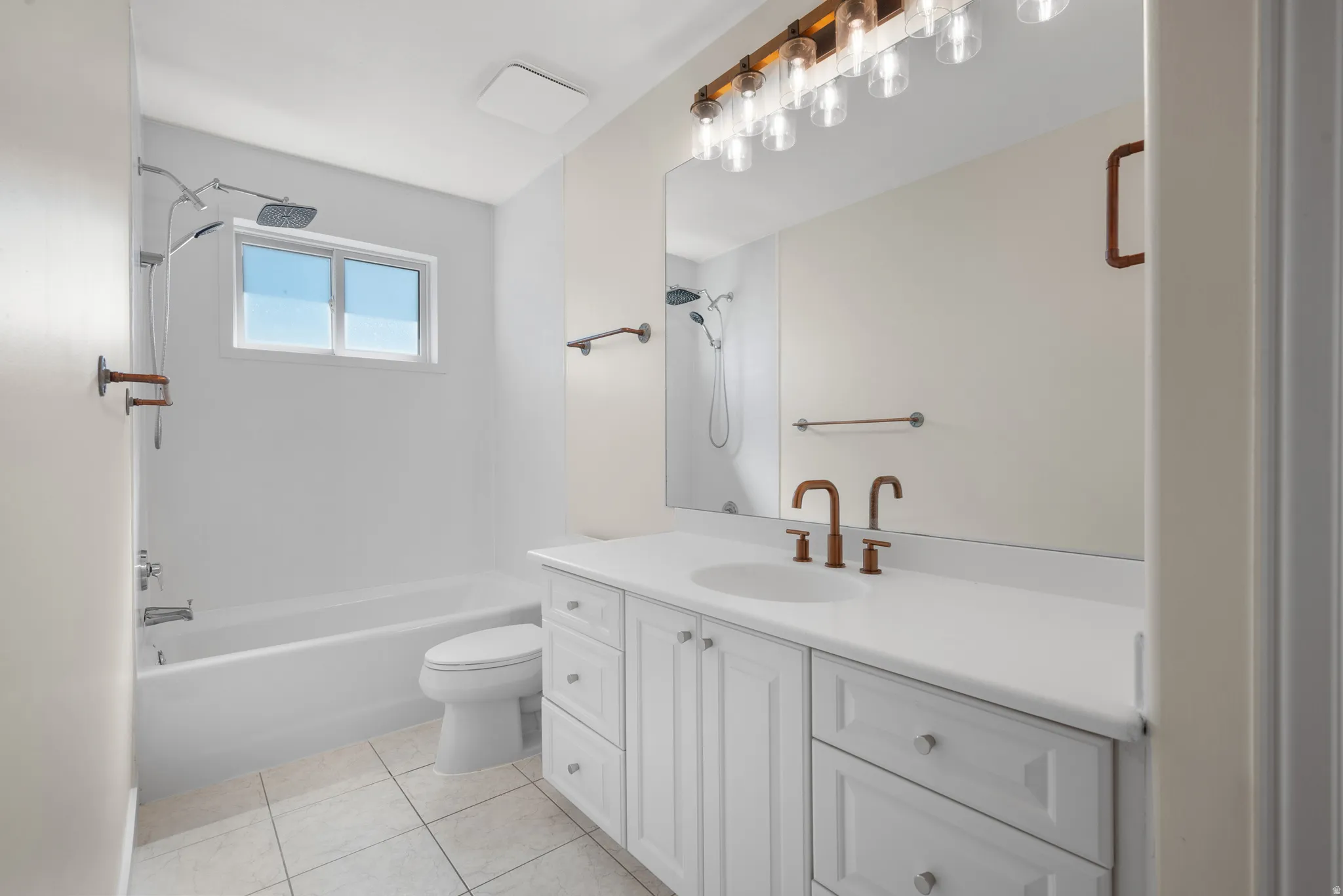 White vanity with integrated sink, white tiled flooring, and bronze-finish fixtures