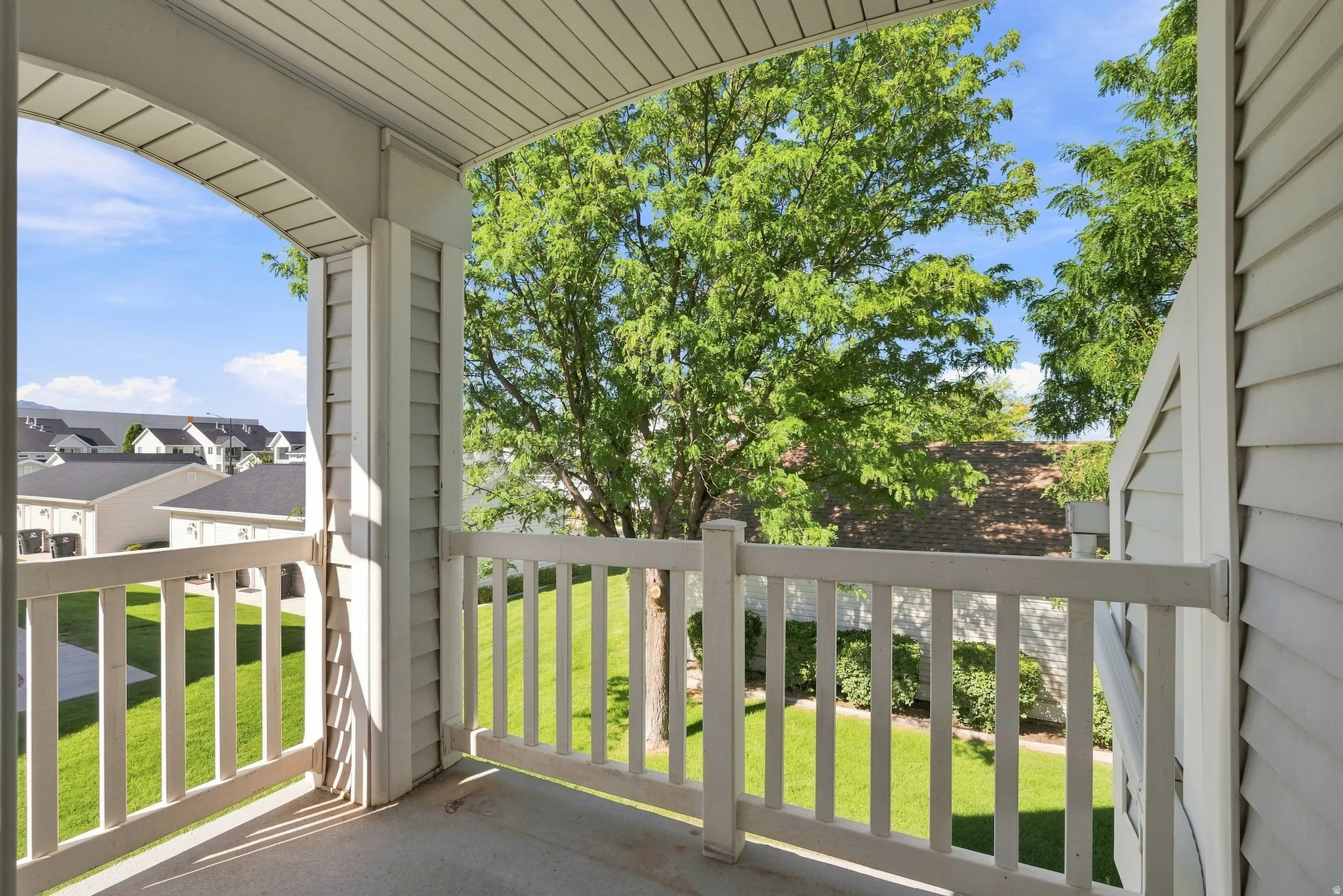 Private balcony featuring a concrete floor, white railing, and an arched ceiling detail