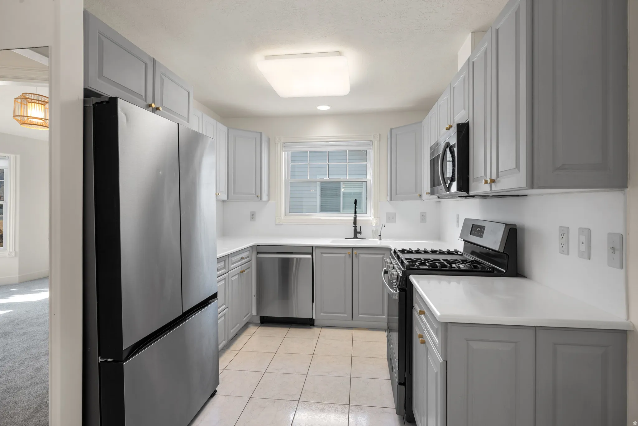 Kitchen featuring light gray cabinetry, white countertops, stainless steel appliances, and tile flooring