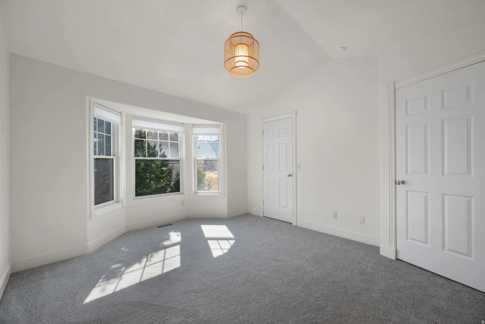 Bay window with white trim, vaulted ceiling, recessed lighting, and a drum pendant light fixture