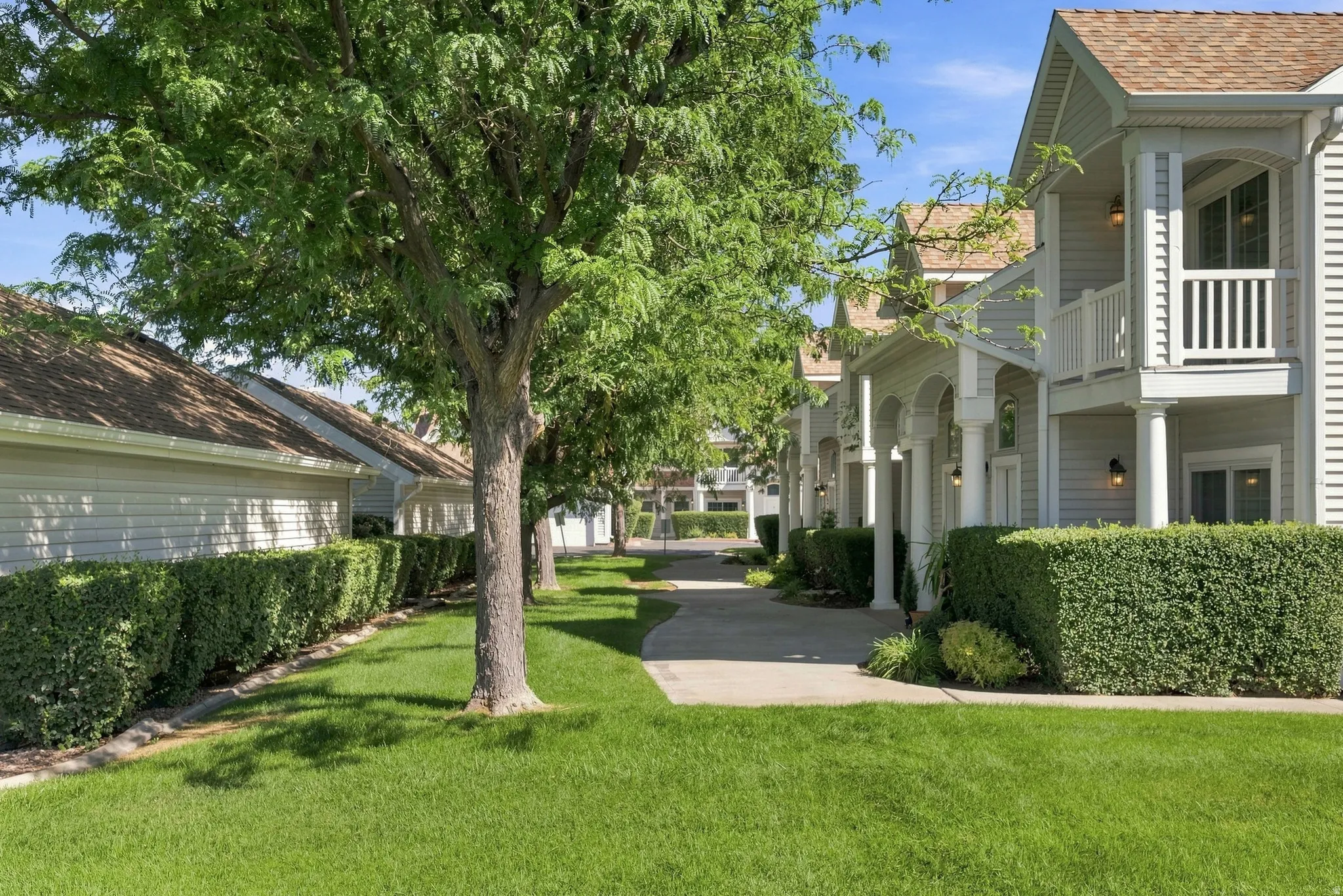 Exterior featuring siding, gabled roofs, second-story balconies with white railings, columned entryways, and mature landscaping