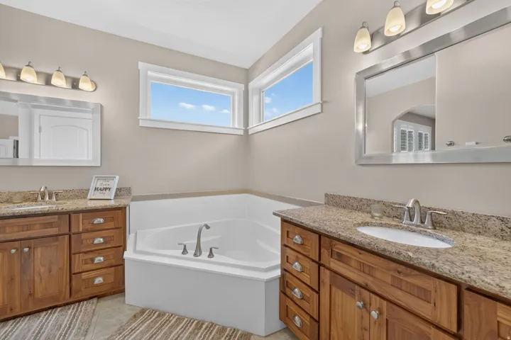 Dual wood-finish vanities with undermount sinks and light-toned countertops