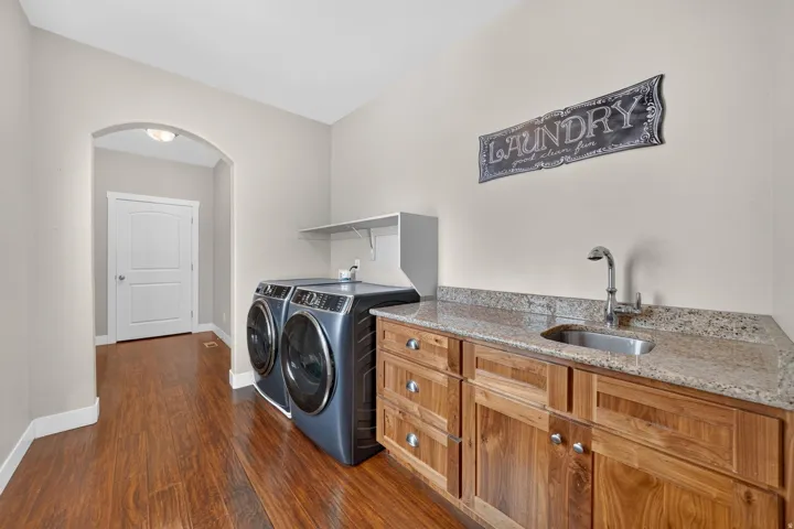 Wood-finish flooring, built-in cabinetry with silver hardware, and a stainless steel sink with a chrome faucet