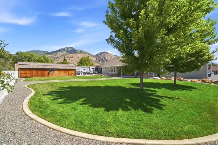 Expansive lawn with mature trees, a gravel pathway, and a large wood-sided barn with a metal roof