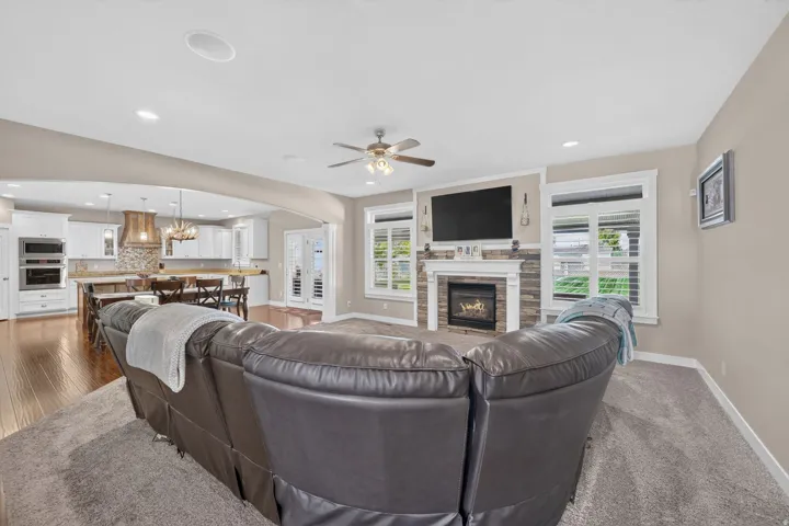 Living area with a stone-surround fireplace, ceiling fan, and recessed lighting