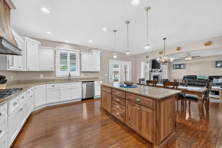 Hardwood-finish flooring, white cabinetry, a wood-finish island with integrated storage, stainless steel appliances, and recessed lighting