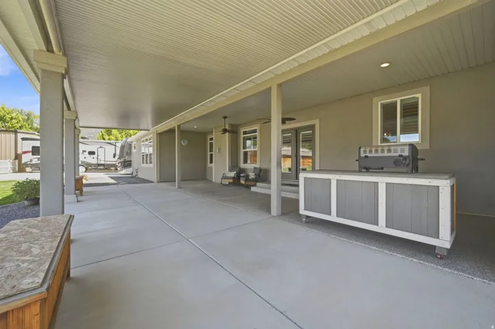 Expansive covered patio featuring a corrugated metal roof, concrete flooring, and white-trimmed support columns