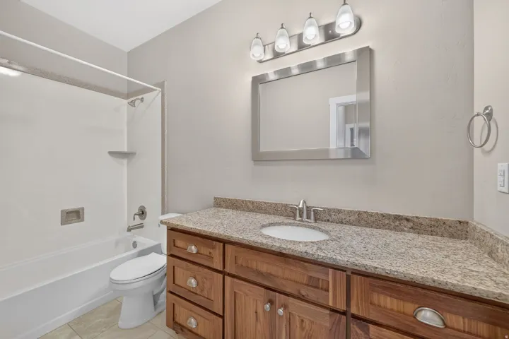 Vanity with a granite-style countertop, wood-finish cabinetry, and an undermount sink