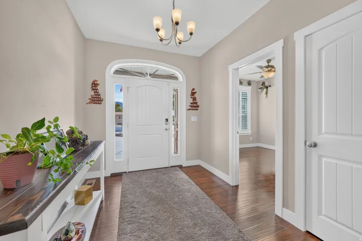 Arched entry door with sidelights, wood-finish flooring, and a decorative chandelier