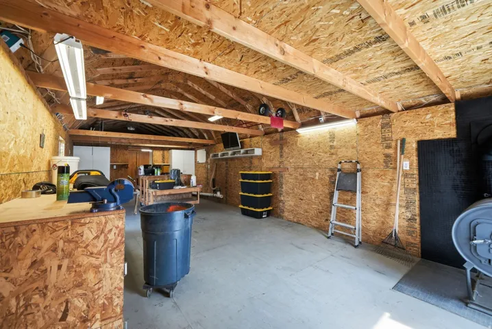 Exposed wood beam ceiling, concrete flooring, built-in shelving, and mounted fluorescent lighting