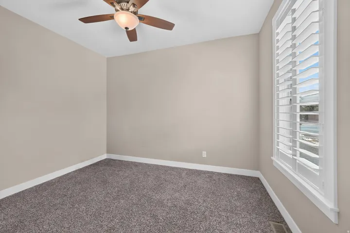 Neutral wall finishes, plush carpet, and a ceiling fan with integrated lighting