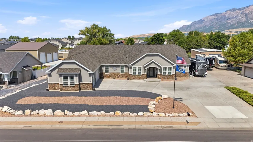 Ranch-style residence featuring a stone and stucco facade, a dark shingle roof, and an attached two-car garage