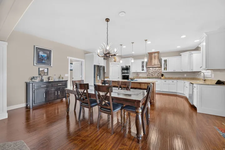 Wood-finish flooring throughout, white cabinetry, integrated double oven, and a built-in kitchen island