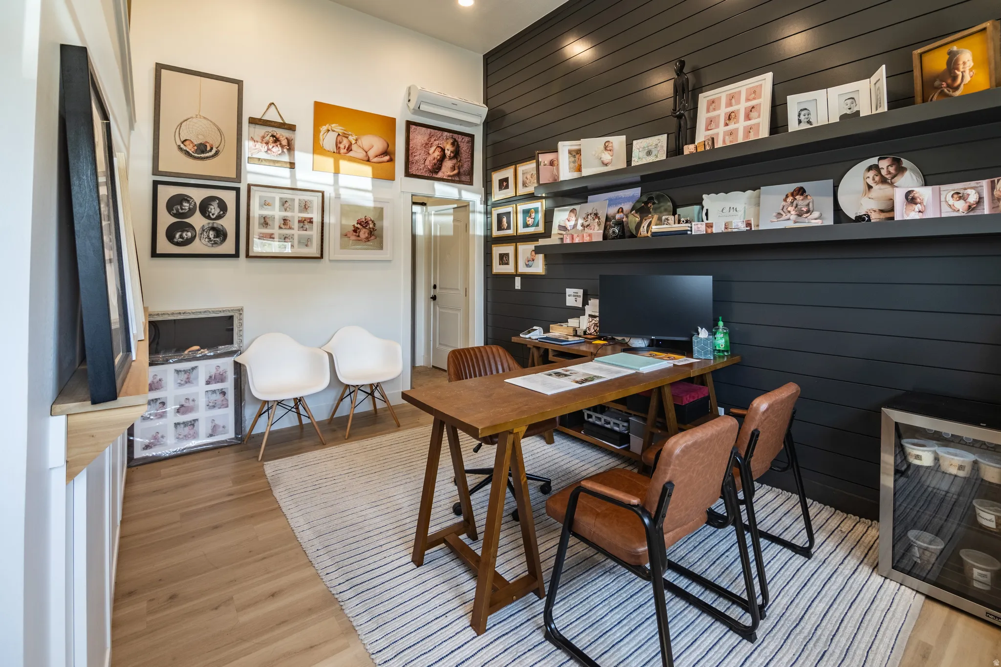 Hardwood-finish flooring, accent wall with horizontal paneling, built-in wall shelving, recessed lighting, and a wall-mounted climate control unit