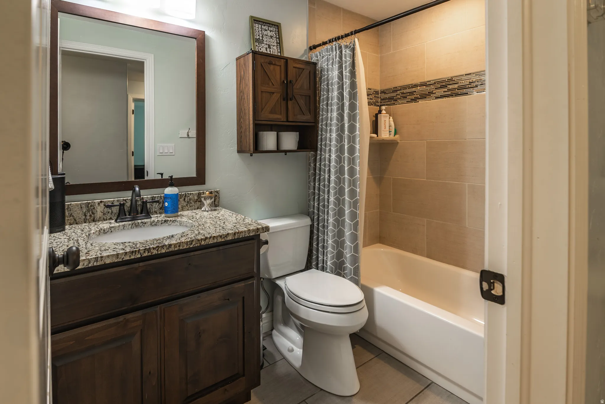 Dark wood-finish vanity with an undermount sink, granite-style countertop, and a framed mirror