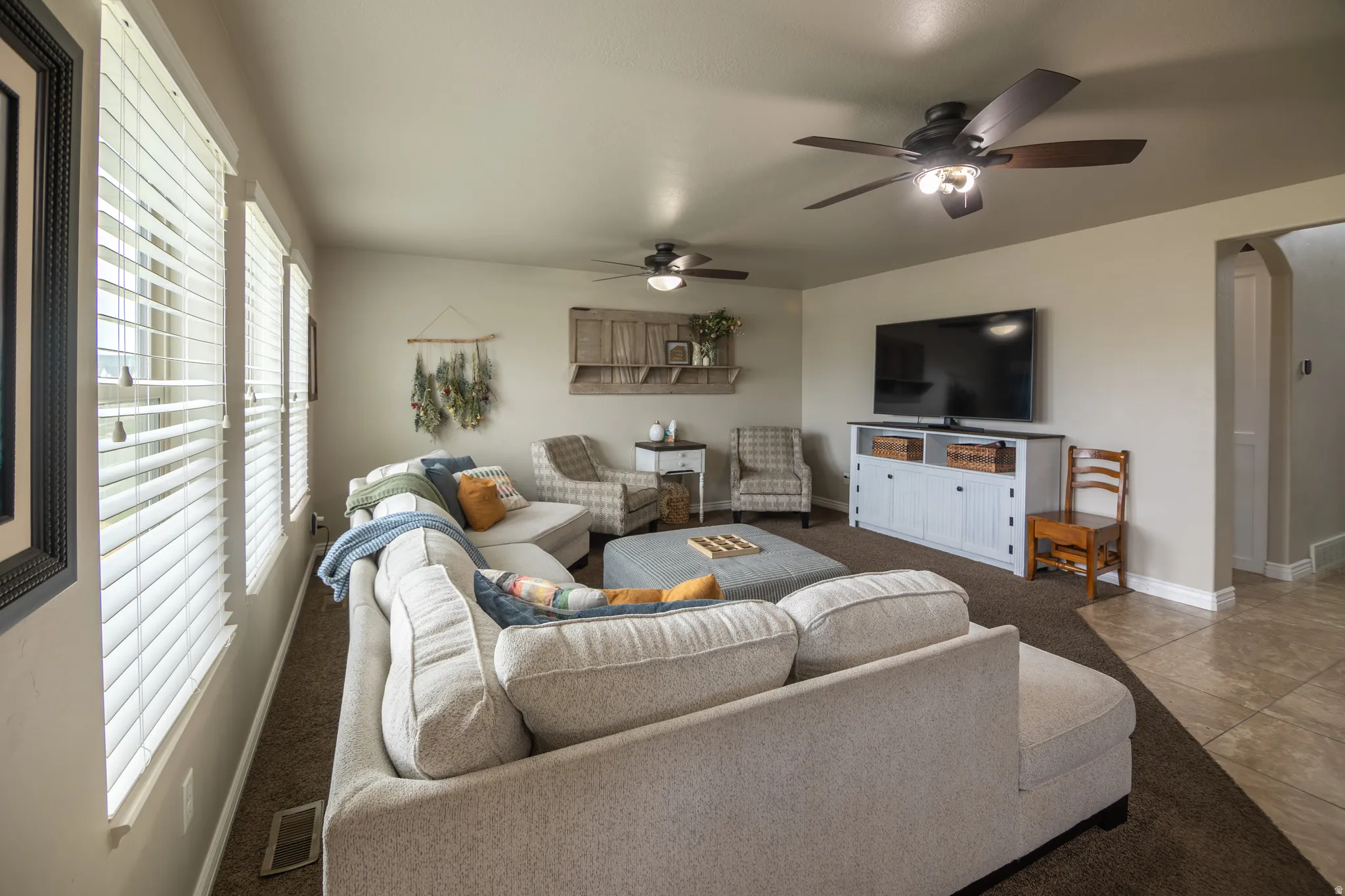 Multiple windows with blinds, two ceiling fans, and a tiled entry