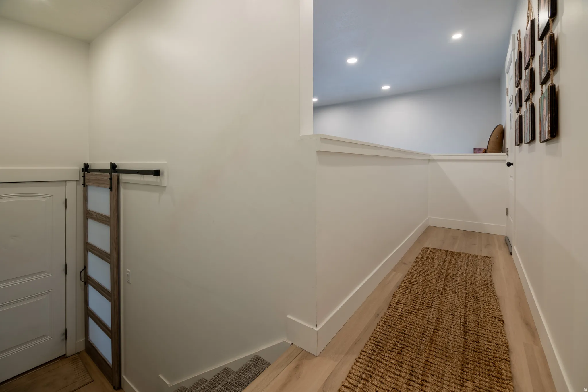 Barn door with frosted glass panels, wood-finish flooring, recessed lighting, and white trim