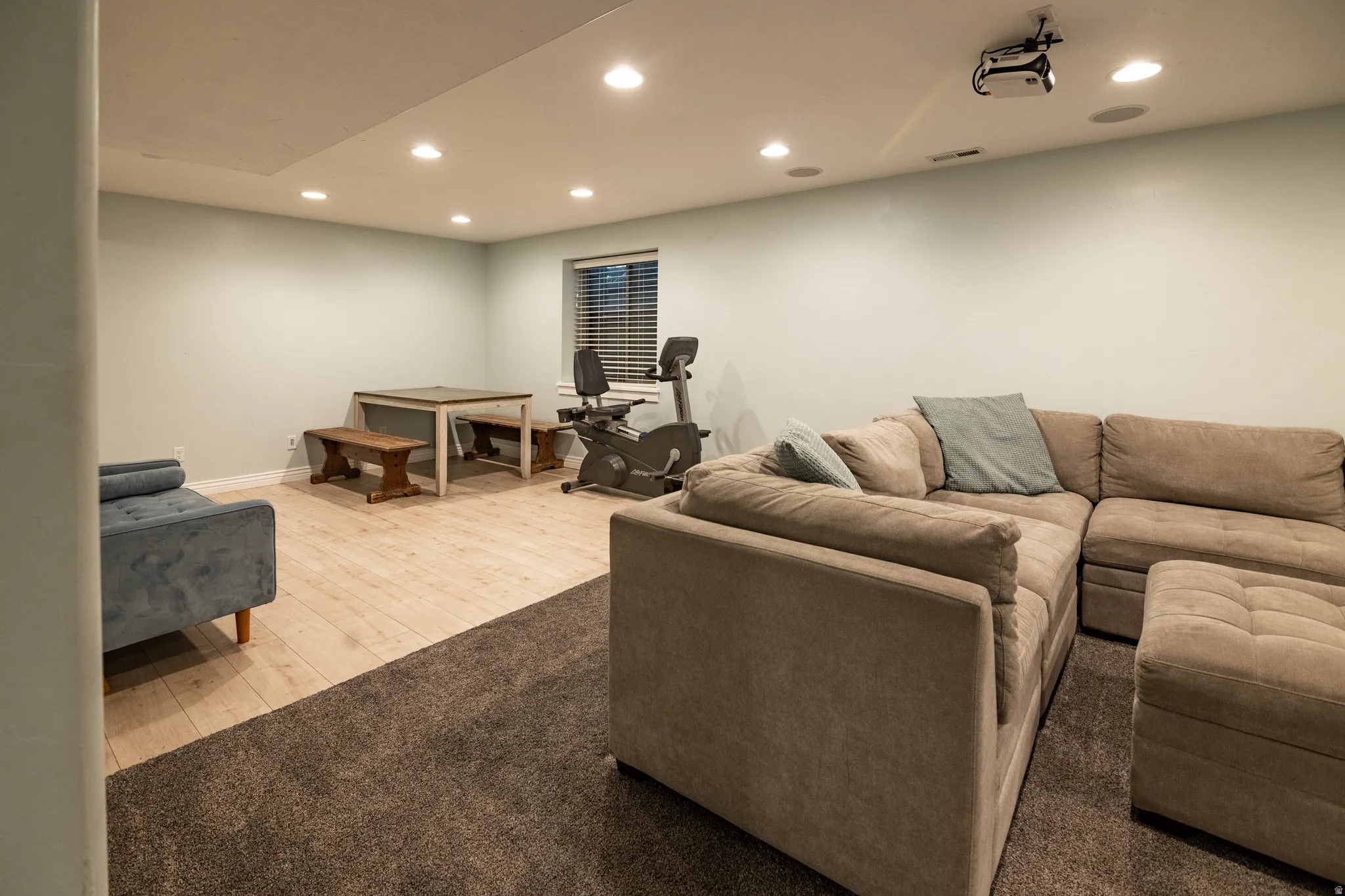 Recessed ceiling lighting, wood-finish flooring, a window with blinds, and a built-in ceiling projector