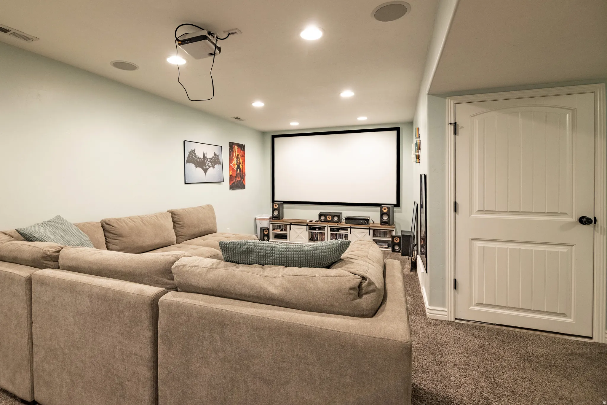 Dedicated media room featuring a large projection screen, recessed ceiling lighting, and built-in ceiling speakers
