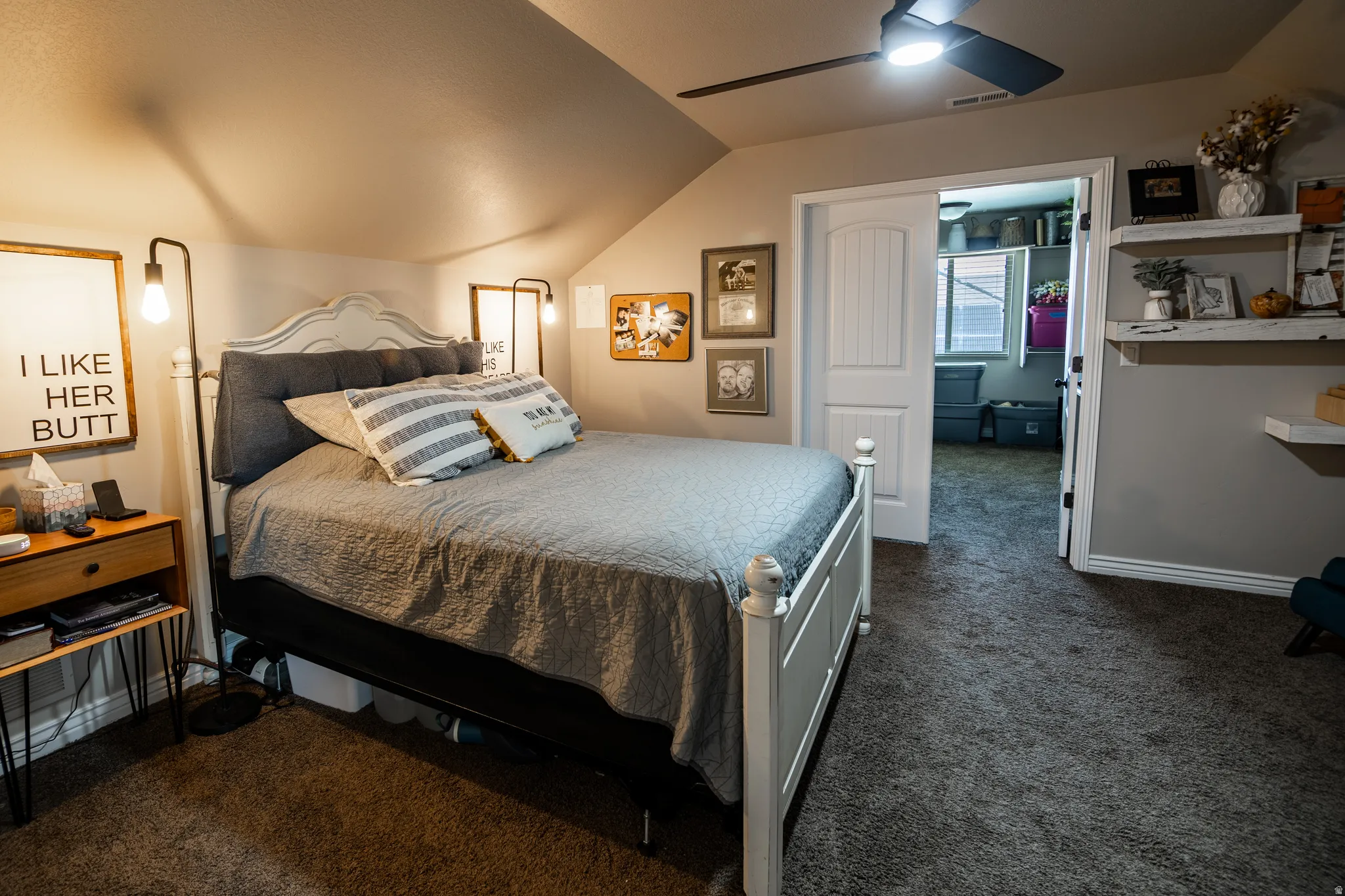 Angled ceiling with sloped walls, ceiling fan, carpet flooring, built-in shelving, and white interior doors