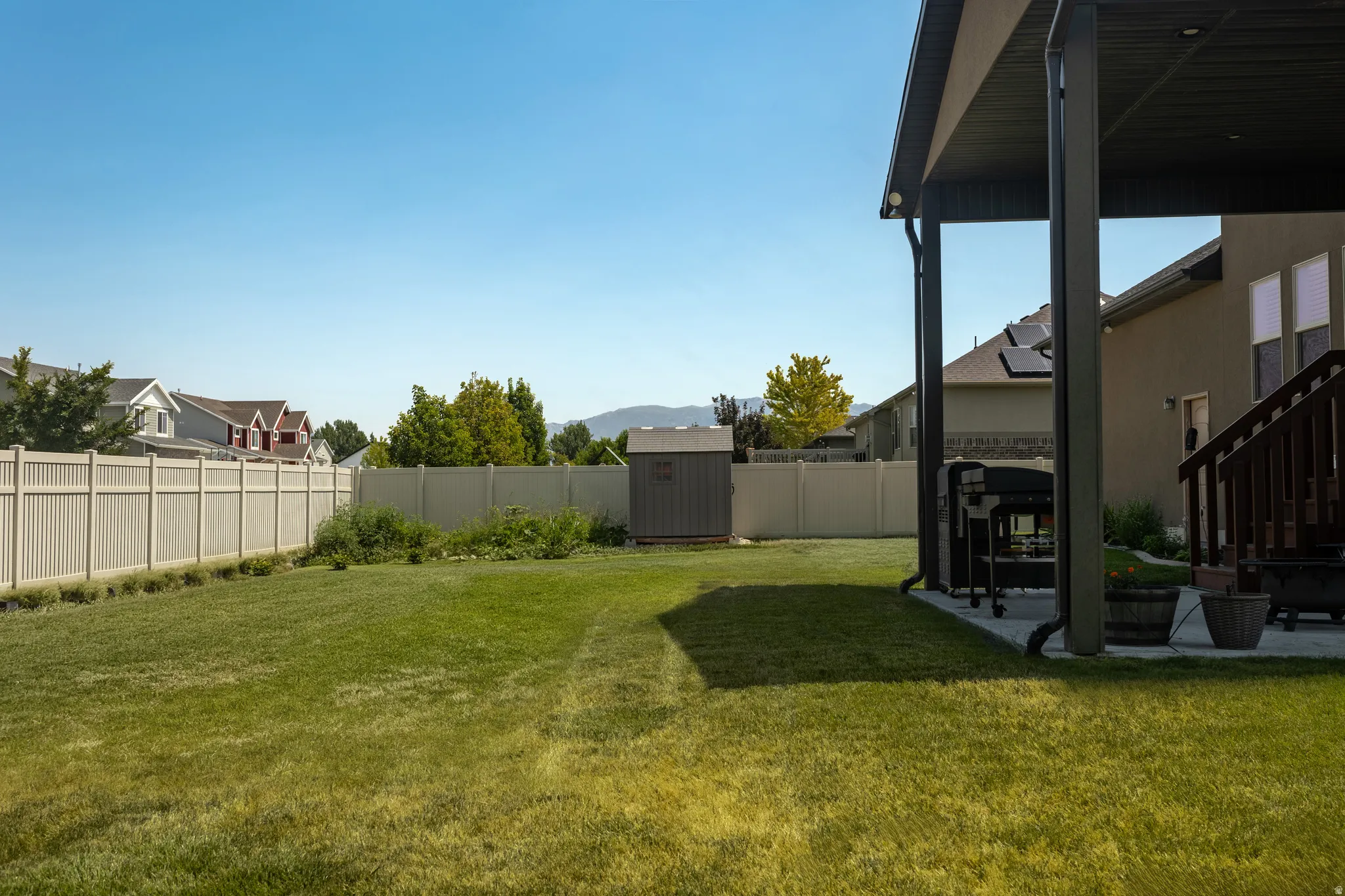 Expansive grassy yard with a covered patio and privacy fencing