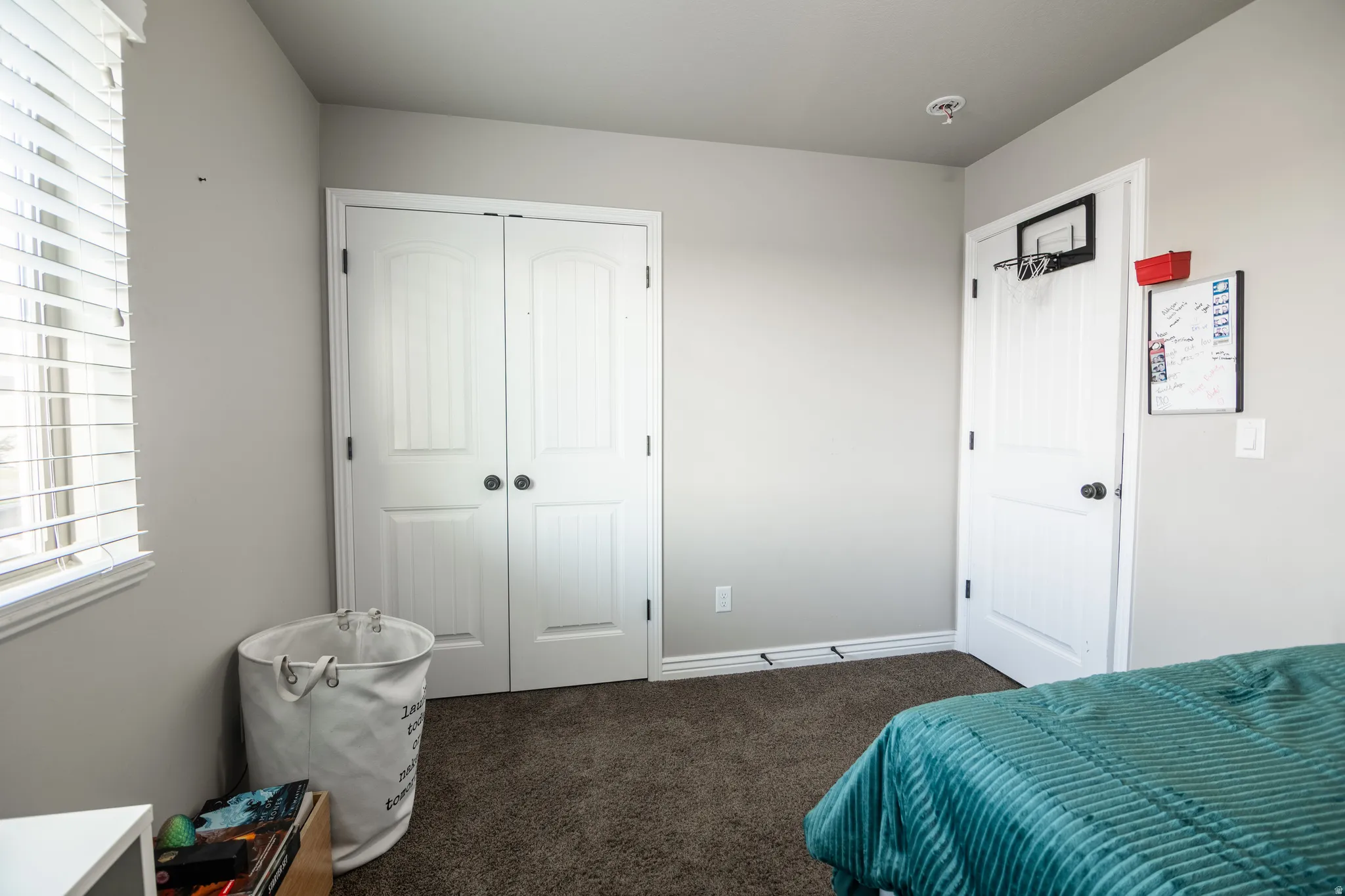 Wall-to-wall carpet flooring, double panel closet doors, window with horizontal blinds, and baseboard trim