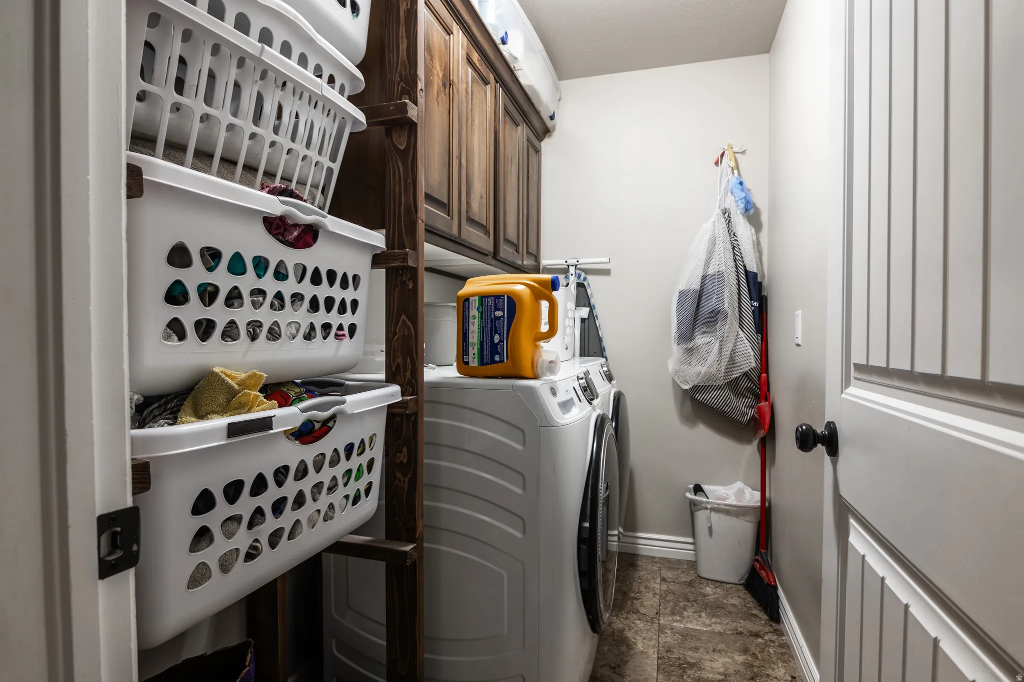 Laundry area featuring wood-finish cabinetry, tile flooring, and a paneled door