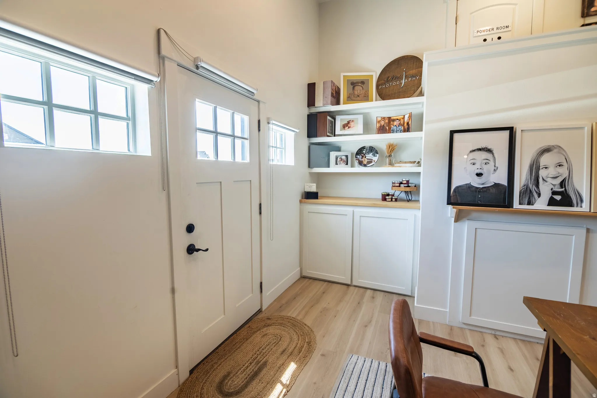 White paneled door with glass inserts, transom windows, built-in shelving, wood-finish flooring, and integrated cabinetry