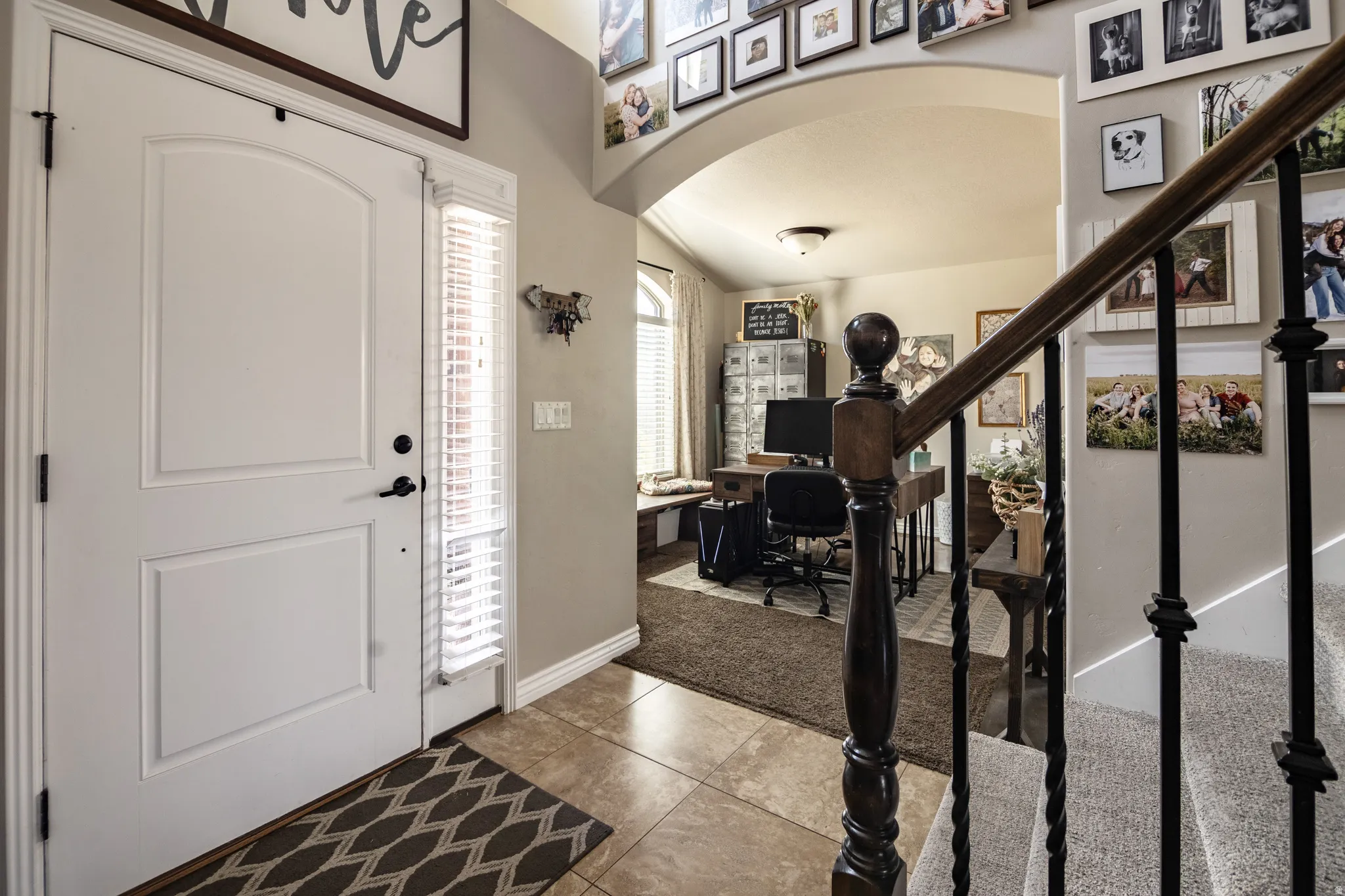 Entryway featuring a paneled door with a sidelight, tiled flooring, and a carpeted staircase with an ornamental wood and wrought iron railing