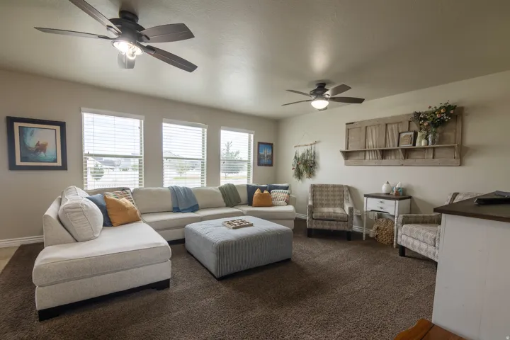 Recessed lighting, multiple windows with blinds, two ceiling fans with integrated lighting, and carpeted flooring