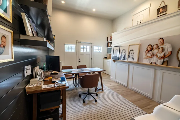 Vaulted ceilings with recessed lighting, light wood-finish flooring, white paneled lower cabinetry, white shaker-style door, and black shiplap accent wall