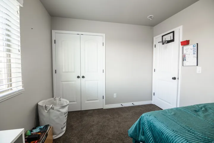 Wall-to-wall carpet flooring, double panel closet doors, window with horizontal blinds, and baseboard trim