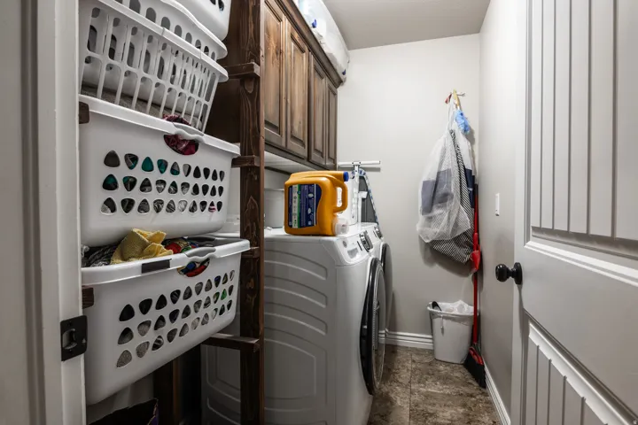 Laundry area featuring wood-finish cabinetry, tile flooring, and a paneled door