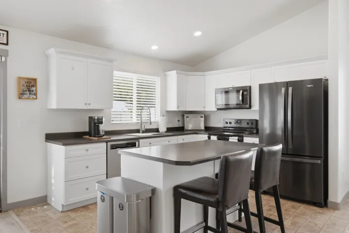 Kitchen featuring white cabinetry, dark countertops, a central island, recessed lighting, and stainless steel appliances