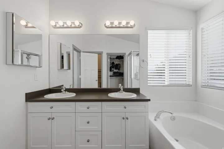 Dual vanity with white cabinetry, integrated sinks, and dark countertops