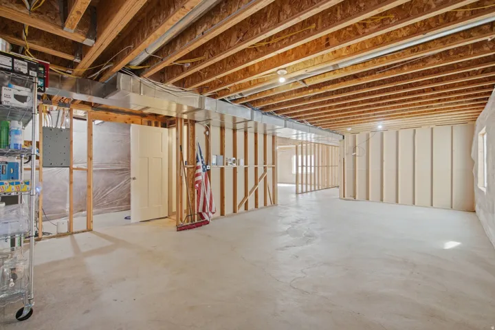 Unfinished basement with exposed wooden joists, concrete flooring, and partial framing