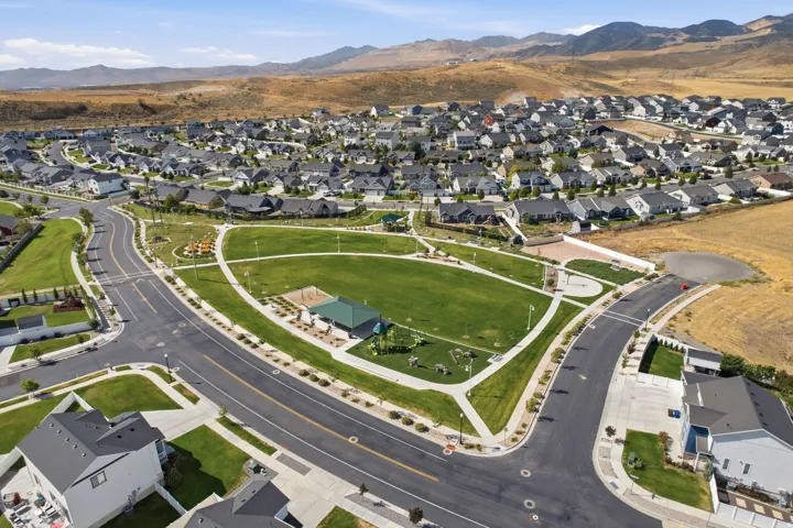 Expansive green space featuring manicured lawns and paved pathways, surrounded by a developed residential community with numerous homes