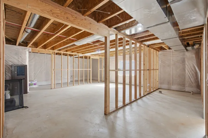 Unfinished basement with concrete flooring, exposed wooden framing, and visible ductwork