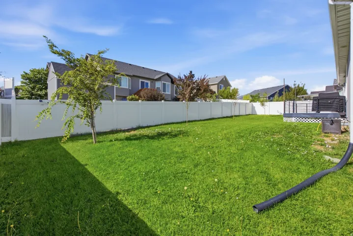 Expansive backyard with a manicured lawn, full-height privacy fencing, and a dedicated patio area