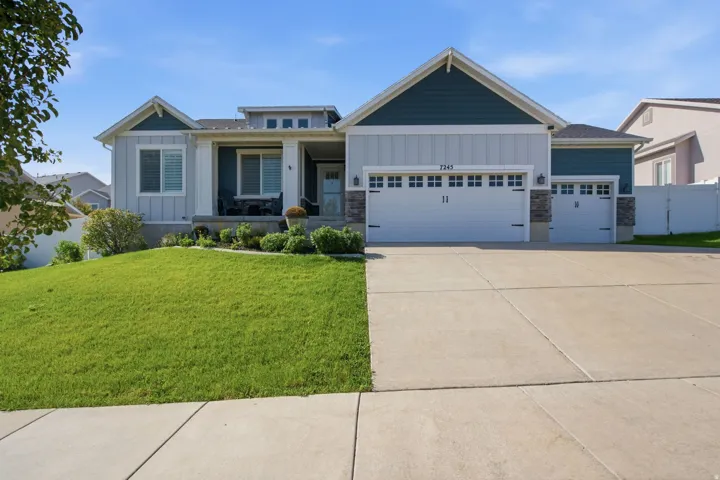 Contemporary exterior with light-colored siding, contrasting teal accents, a covered front porch, an attached two-car garage, and a concrete driveway